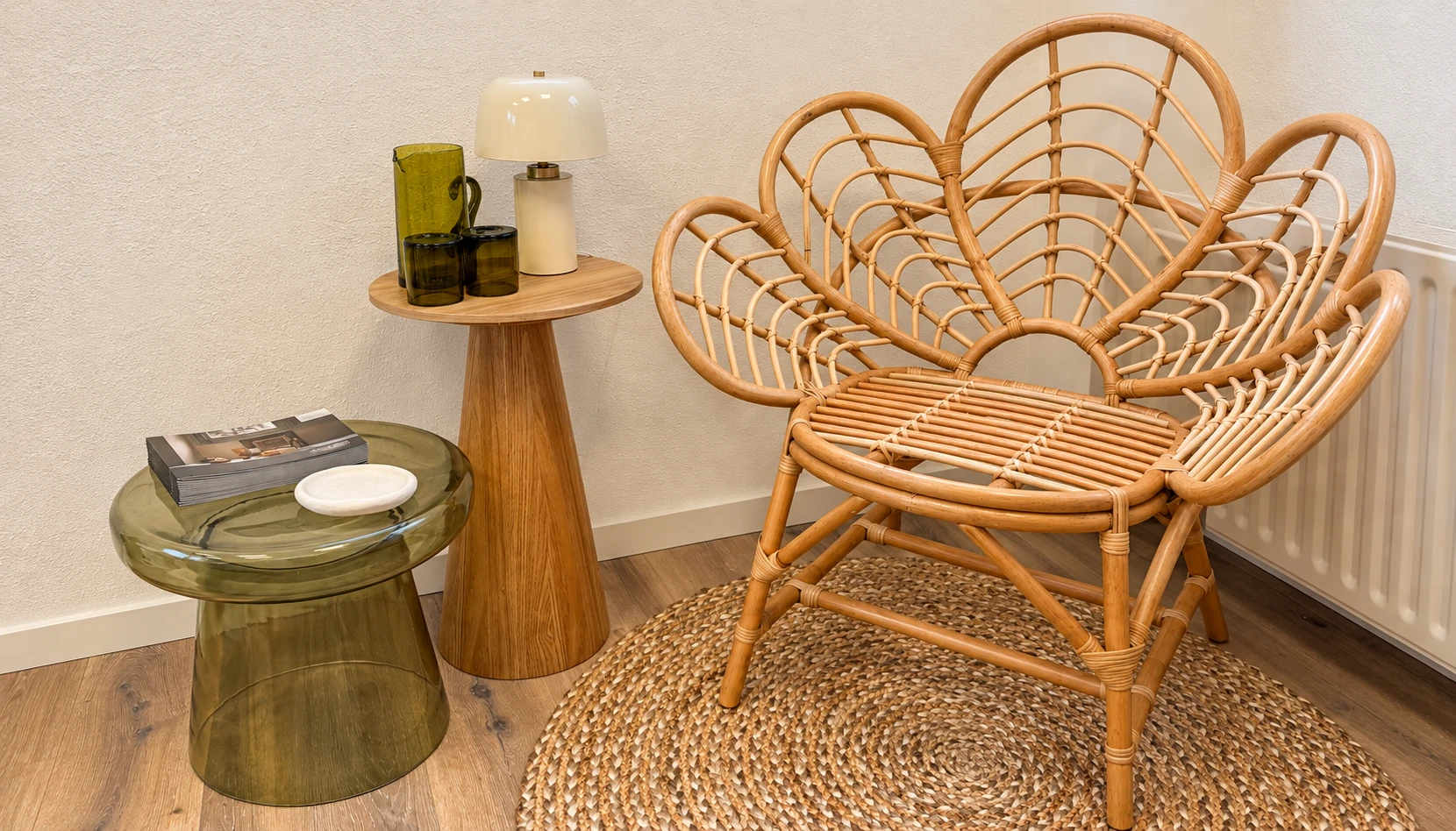 Het warme zithoekje van de praktijk, met rotan stoel en groene glazen bijzettafel
